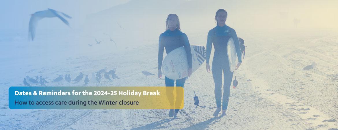 Two female students holding surfboards on the beach